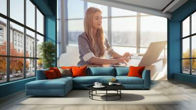 young beautiful female copywriter typing texts and blogs in spacious light office, her workplace, us Wall mural