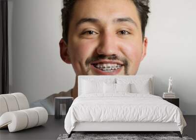 Portrait of a young man with braces smiling. A happy young man with braces on a white background Wall mural