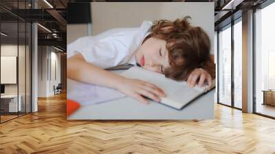 The boy fell asleep in the classroom sitting at a school desk Wall mural