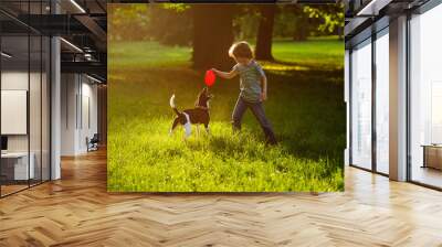 The boy of 8-9 years trains in park with the dog. Wall mural