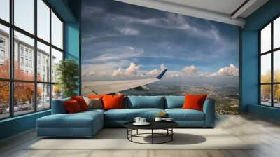 Airplane flying above clouds in aircraft wing on blue sky background. Wall mural