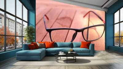 Glasses with black frames on a brown wooden table Wall mural