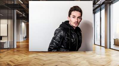 Attractive elegant man in stylish black leather jacket posing on light gray background. Wall mural