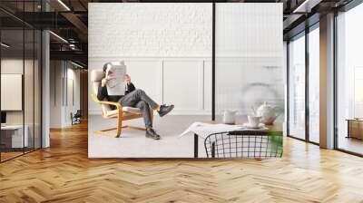 Rocker chair in the white room, man is reading newspaper, brick and classic wall background, chamber, green plant leaf close up blur, working table. Wall mural