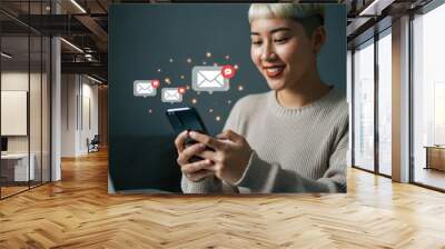 Woman using smartphone, laptop in background, beige sweater, long dark hair, closeup shot, soft lighting, teal wall, digital lifestyle, modern technology, casual indoor setting, focused expression, te Wall mural