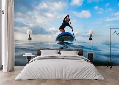 Young woman on the sea with a paddle surf board Wall mural