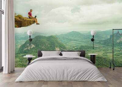 Man working with laptop sitting on the rocky mountain on beautiful scenic clif background. Thailand. Krabi . Wall mural