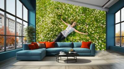 Young beautiful woman relaxing in the field with flowers. Overhead view. Wall mural