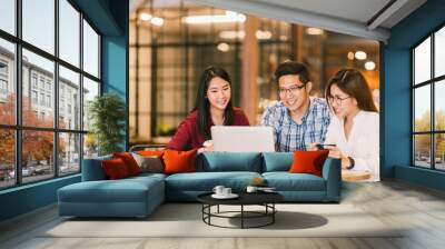 Young Asian college students group or coworkers using laptop computer together at cafe or university. Casual business, freelance work, coffee break meeting, e-learning or e-commerce activity concept Wall mural