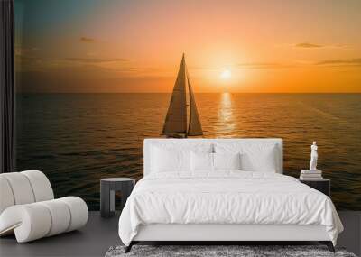 a sailboat sailing in the sea at sunset Wall mural