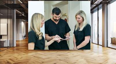 A male physician doctor at a medical spa and wellness clinic speaking to two female nurse practitioners Wall mural