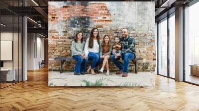 Blended family of five with two girls and a baby boy sitting on a table by an urban old brick wall Wall mural