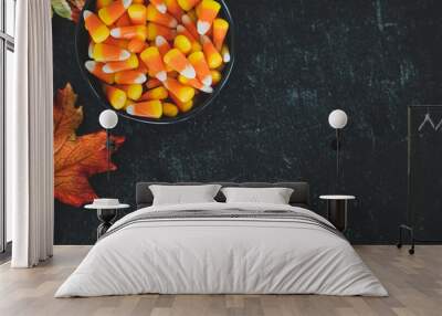 bowl of autumn fall halloween candy corn spilled on black slate with fall autumn leaves decor decoration with copy space Wall mural