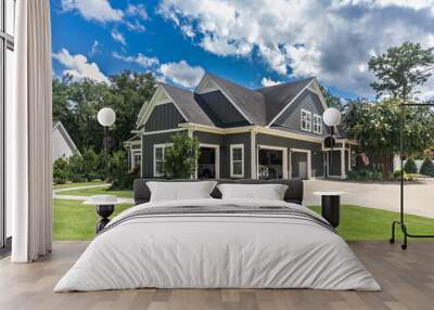 The side view of a large gray craftsman new construction house with a landscaped yard a three car garage and driveway Wall mural