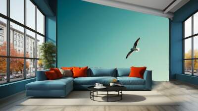 A solitary bird flying in a clear blue sky Wall mural