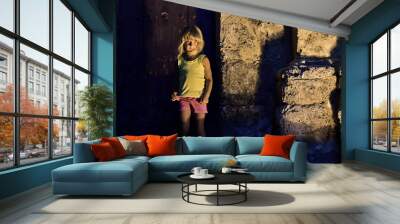 Night shot of little girl leaning against old building at street Wall mural