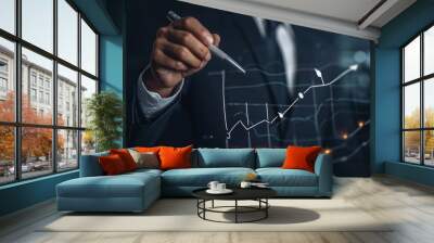 A business professional in a suit uses a pen to interact with a digital graph showcasing financial growth trends against a dark office backdrop filled with city lights Wall mural