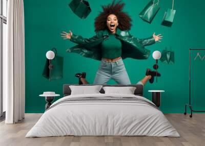 Full size picture of funny excited amazed shocked brunette curly girl hold bags on travel have bargains jump run wear green jacket denim style stylish trendy jeans isolated over green color background Wall mural