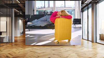 Female traveler sleeping or lying on chairs in the airport terminal Wall mural