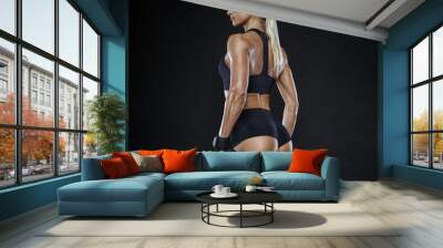 Fitness woman in training pumping up muscles with dumbbell Wall mural