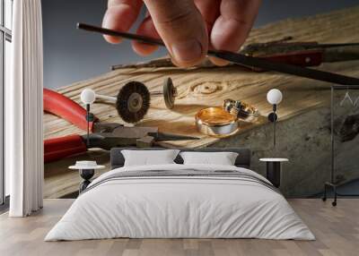 Jewelry craftsmanship desk. Jeweller mans hand close-up. The jeweller polishing tools and two tone rose gold and white gold wedding rings. Focus on rings Wall mural