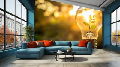 Small plant growing inside a light bulb at sunset symbolizing green energy Wall mural