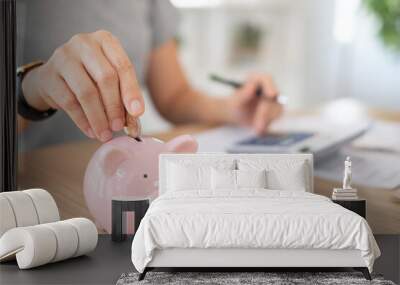 savings and finance. women put coin into the piggy bank Wall mural