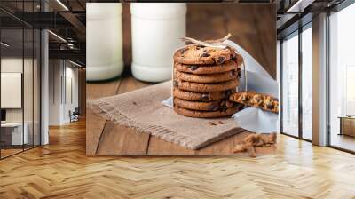 A stack of cookies with milk chocolate and two bottles of milk on a wooden table Wall mural