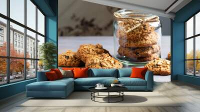 Flourless gluten free peanut butter, oatmeal and chocolate chips cookies in glass jar and on table, horizontal Wall mural