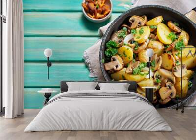 Fried potatoes with mushrooms, onions and parsley served in a frying pan with turquoise wooden background Wall mural