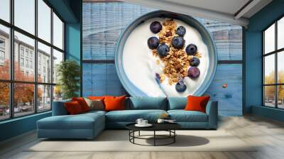 Greek yogurt with blueberries and granola, downward view on a rustic soft blue wood background Wall mural