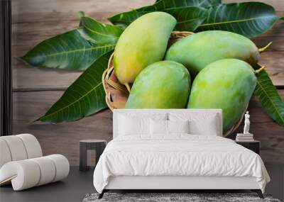 Green mango and green leaf on basket and old wooden floor background, Group of raw mangoes organic with sour and high vitamin C fruit for healthy. Wall mural