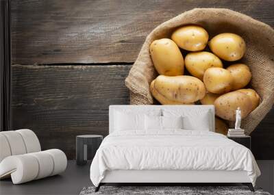 Raw potato food . Fresh potatoes in an old sack on wooden background. Free place for text. Top view Wall mural