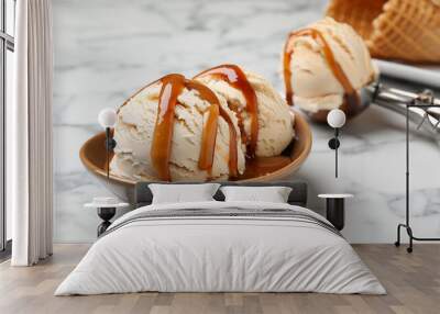 Scoops of ice cream with caramel sauce and cone on white marble table, closeup. Space for text Wall mural