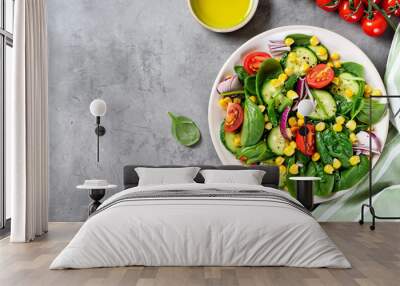 Spring vegan salad with spinach, cherry tomatoes, corn salad, baby spinach, cucumber and red onion. Healthy food concept. Gray stone table. Top view. Copy space Wall mural