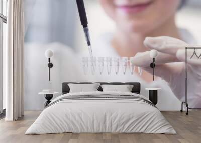 Close-up of female technician with multipipette and in genetic laboratory doing PCR research. Young woman is genetics scientist and she loads saliva samples for DNA amplification Wall mural