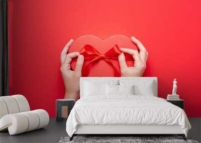 Close up on female hands holding a gift in a pink heart presents for valentine day, birthday, mother's day. Flat lay. Symbol of love. Valentines day background with a gift boxes on concrete board. Wall mural