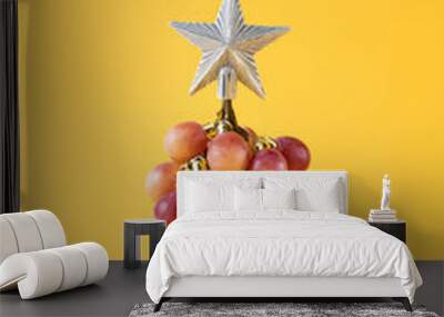 Conceptual idea for celebration tropical New Year with bunch of grapes as Christmas fir tree and star on yellow background Wall mural