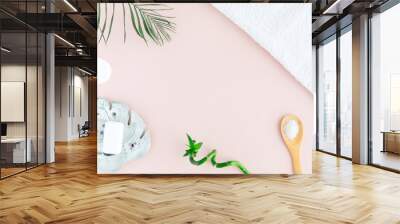 Flat lay and top view of white towel, jar of cream, green palm leaves and bamboo on pastel pink background. Products for spa treatment Wall mural