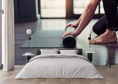 Yoga concept. Young men rolling mat after a yoga on black wooden floor Wall mural