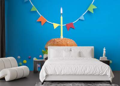 festive cheeseburger with candle and colorful confetti  close up on blue background Wall mural