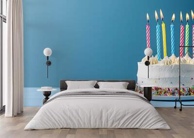 A white birthday cake with colorful candles against a blue background, copy space concept for a Happy Birthday celebration banner template design.  with empty copy space Wall mural