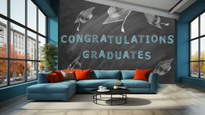 Hand drawing text CONGRATULATIONS GRADUATES and graduation caps on blackboard. Wall mural