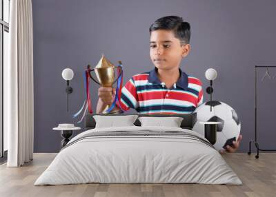 Indian school boy holding a golden trophy cup and football	
 Wall mural