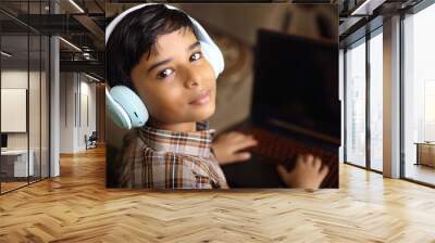 Portrait of Indian little boy using laptop while attending the online class at home Wall mural