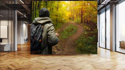 A man with backpack walks in the amazing autumn forest. Hiking alone along autumn forest paths. Travel concept. Wall mural