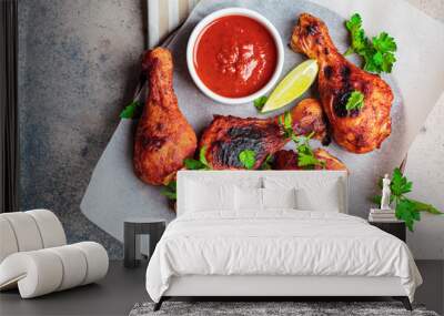 Baked chicken legs in spicy tomato sauce on wooden plate, top view. Wall mural