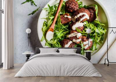 Beetroot Falafel with tahini dressing and arugula in a white bowl, top view. Healthy vegan food concept. Wall mural