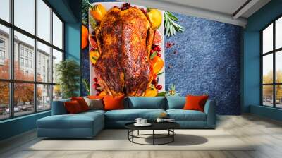 Christmas baked duck with herbs and fruits on gray plate, blue background, top view. Wall mural