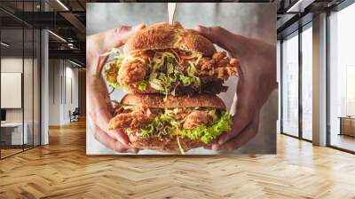 Crispy fried chicken sandwiches with coleslaw salad in man hands. Wall mural